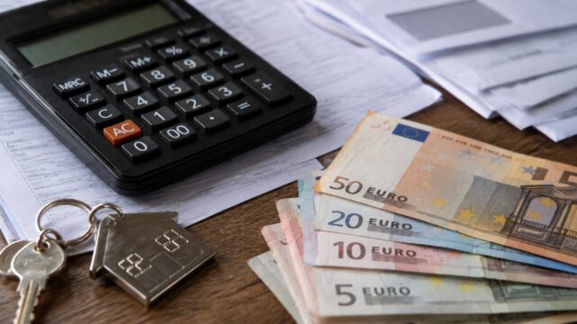 Taschenrechner, Hausschlüssel und Euro-Scheine auf Unterlagen – Symbolbild zur Wohngeld-Berechnung 2027
