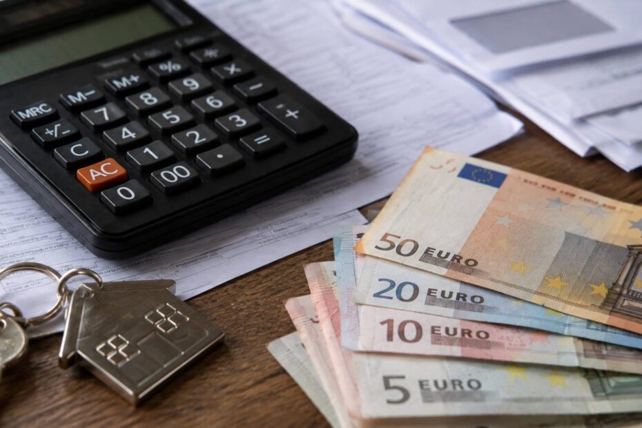Taschenrechner, Hausschlüssel und Euro-Scheine auf Unterlagen – Symbolbild zur Wohngeld-Berechnung 2027